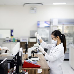 two women working in lab with coats and face masks